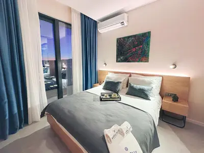 a bedroom with a large bed with blue curtains at Royal Blue Resort & Residences in Tivat