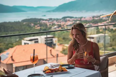a woman sitting at a table with a plate of food at Royal Blue Resort & Residences in Tivat