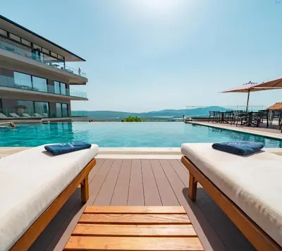 a swimming pool with two beds in front of a building at Royal Blue Resort & Residences in Tivat