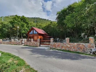 a log cabin with a stone wall next to a road at Villa Skyline in Kotor
