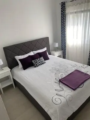 a bedroom with a large bed with purple pillows at Apartments Vuksanovic in Bar
