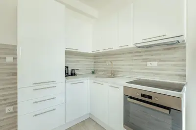 a white kitchen with white cabinets and a sink at Apartment Ava in Kotor