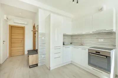 a white kitchen with white cabinets and a wooden floor at Apartment Ava in Kotor