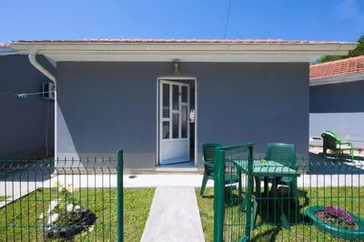 a house with a green fence with a table and chairs at Studios Merdović in Budva