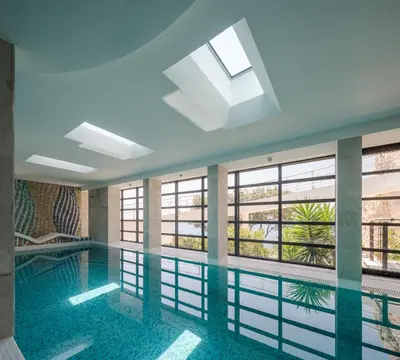 a swimming pool in a building with windows at CONTiNUUM in Ulcinj