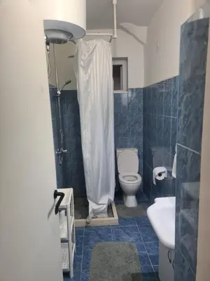 a blue tiled bathroom with a toilet and a sink at Serenity City Centre in Podgorica