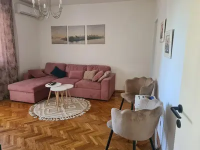 a living room with a pink couch and a table at Serenity City Centre in Podgorica