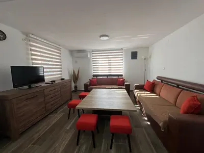 a living room with a couch and a table with red chairs at Gazdinstvo Đurović in Dobra Voda