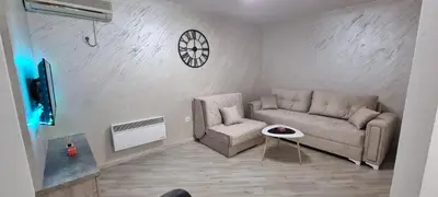 a living room with a couch and a chair and a clock at Stan apartman Lana Budva in Budva
