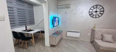 a living room with a table and a clock on the wall at Stan apartman Lana Budva in Budva
