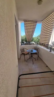 a balcony with a table and chairs and two windows at Apartmani MINA in Bar
