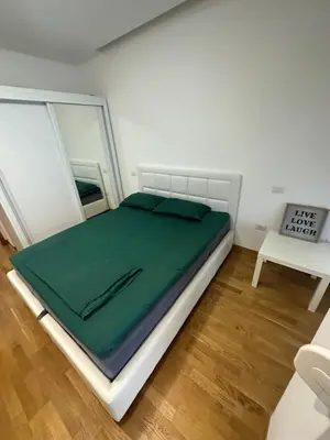a bed in a room with a green blanket on it at Laura apartment City kvart in Podgorica