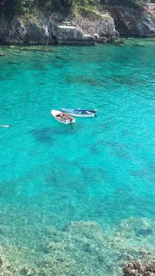 two boats are sitting in the blue water at Apartments Misko in Utjeha