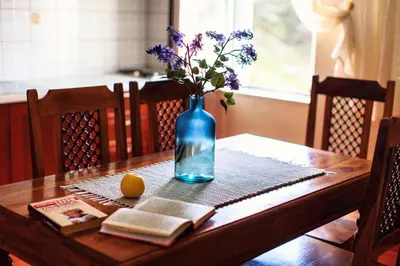 a table with a blue vase with flowers and a book at Apartments Misko in Utjeha