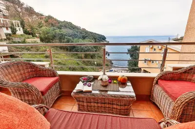 a balcony with wicker chairs and a table with a view at Apartments Misko in Utjeha