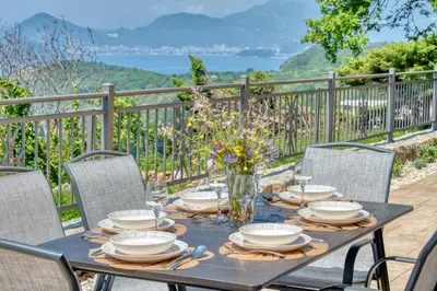 a table with chairs and a table with a vase of flowers at Seaview Villa Lavanda with pool in Budva