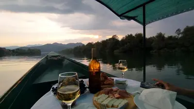 a table with a bottle of wine and glasses on a boat at Apartment Dapcevic Skadar lake in Vranjina
