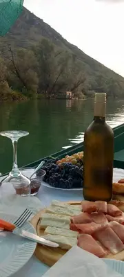 a table with a bottle of wine and a plate of food at Apartment Dapcevic Skadar lake in Vranjina