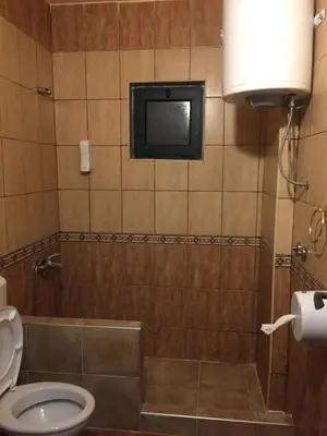 a bathroom with a toilet and a tv on the wall at Guesthouse Liamra in Ulcinj
