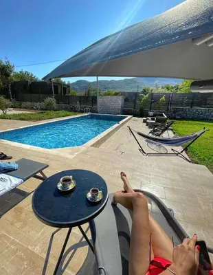 a woman laying on a chair next to a pool at Green House in Virpazar