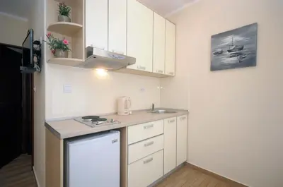a small kitchen with white cabinets and a sink at Apartments Royal in Budva