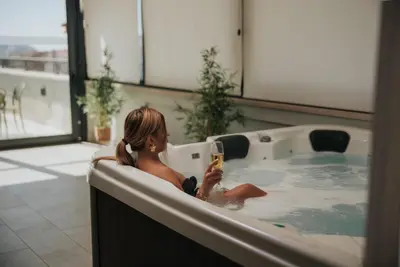 a woman sitting in a bath tub with a glass of wine at Hotel Diplomat by Aycon in Budva