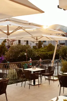 a table and chairs with umbrellas on a patio at Hotel Diplomat by Aycon in Budva