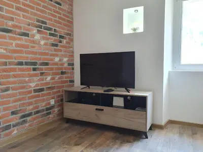 a flat screen tv sitting on a wooden stand next to a brick wall at Apartman Pontica in Kotor