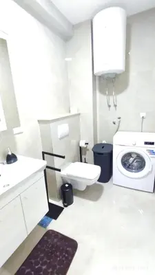 a bathroom with a toilet and a washing machine at Apartments LORA Susanj in Bar