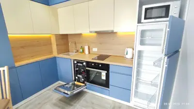 a small kitchen with blue cabinets and a refrigerator at Apartments LORA Susanj in Bar