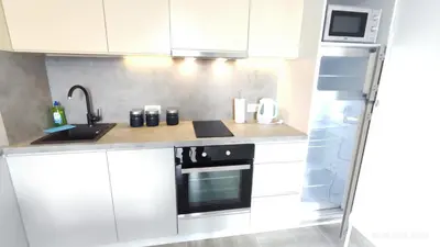 a kitchen with white cabinets and a sink and a refrigerator at Apartments LORA Susanj in Bar
