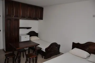 a room with two beds and a table and chairs at Rooms & Apartments Anka in Bar