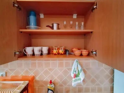 a kitchen with a counter with bowls and dishes on shelves at Apartmani LJUBICA in Utjeha