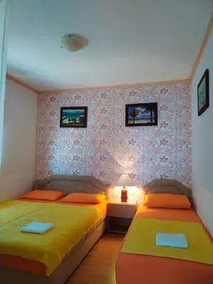 a bedroom with two beds and a wall with wallpaper at Apartmani LJUBICA in Utjeha