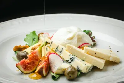 a white plate of food with cheese and fruit at Mali Hotel Porat in Budva