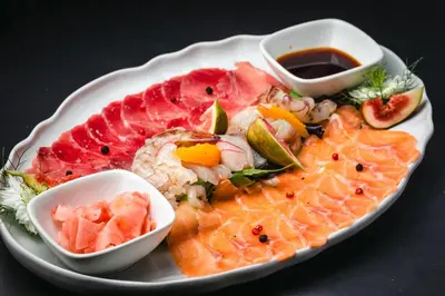 a plate of food with sushi and fruit on a table at Mali Hotel Porat in Budva