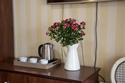 a white vase with pink flowers on a table at Mali Hotel Porat in Budva