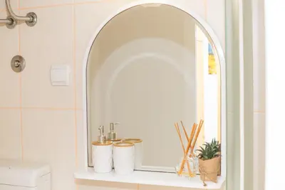 a bathroom with an oval mirror on a shelf at Apartmani F&M in Kotor