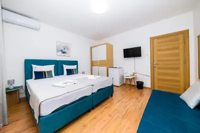 a bedroom with a large bed with a blue headboard at Apartmani F&M in Kotor