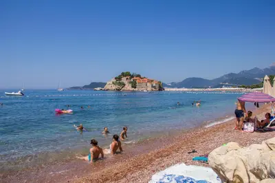 a group of people in the water at a beach at Montesan Luxury Apartment Beach Front in Sveti Stefan