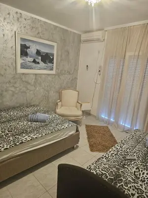 a bedroom with two beds and a chair at Apartmani Sabotic in Sutomore