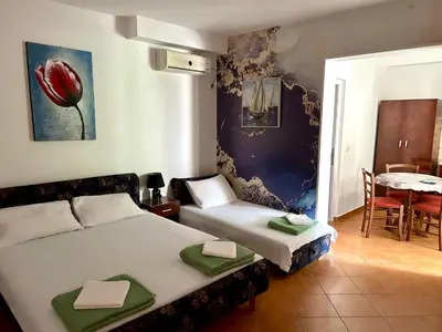 a bedroom with two beds and a table and a table and chairs at Apartmani Vedrana in Sutomore