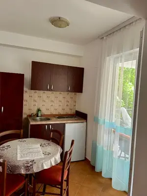 a kitchen with a table and a table and a window at Apartmani Vedrana in Sutomore
