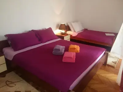 a bedroom with two beds with purple sheets and towels at Lazar Apartments in Petrovac na Moru