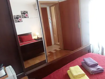 a bedroom with a mirror and a bed with a red blanket at Lazar Apartments in Petrovac na Moru