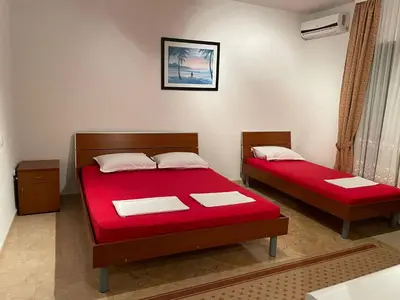 two beds with red sheets in a room at Apartments Zati in Ulcinj
