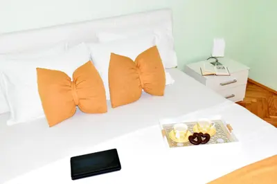 a white bed with orange pillows and a tray on it at Apartment City View in Kotor