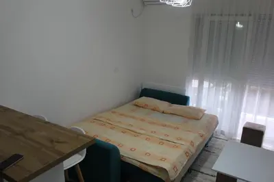 a small bedroom with a bed and a table at Jelena apartment Bar in Bar