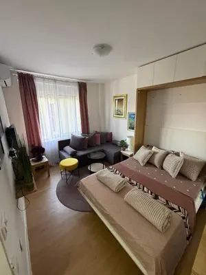 a bedroom with a large bed and a living room at Moderan Studio na Trgu Republike - Centar in Podgorica