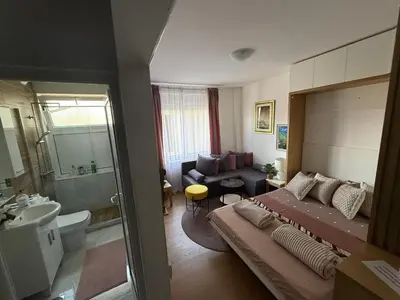 a bedroom with a large bed and a bathroom at Moderan Studio na Trgu Republike - Centar in Podgorica